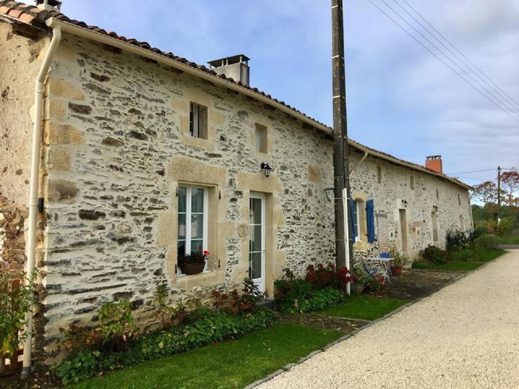 an old stone building with flowers in front of it at La Bucherie in Montembœuf