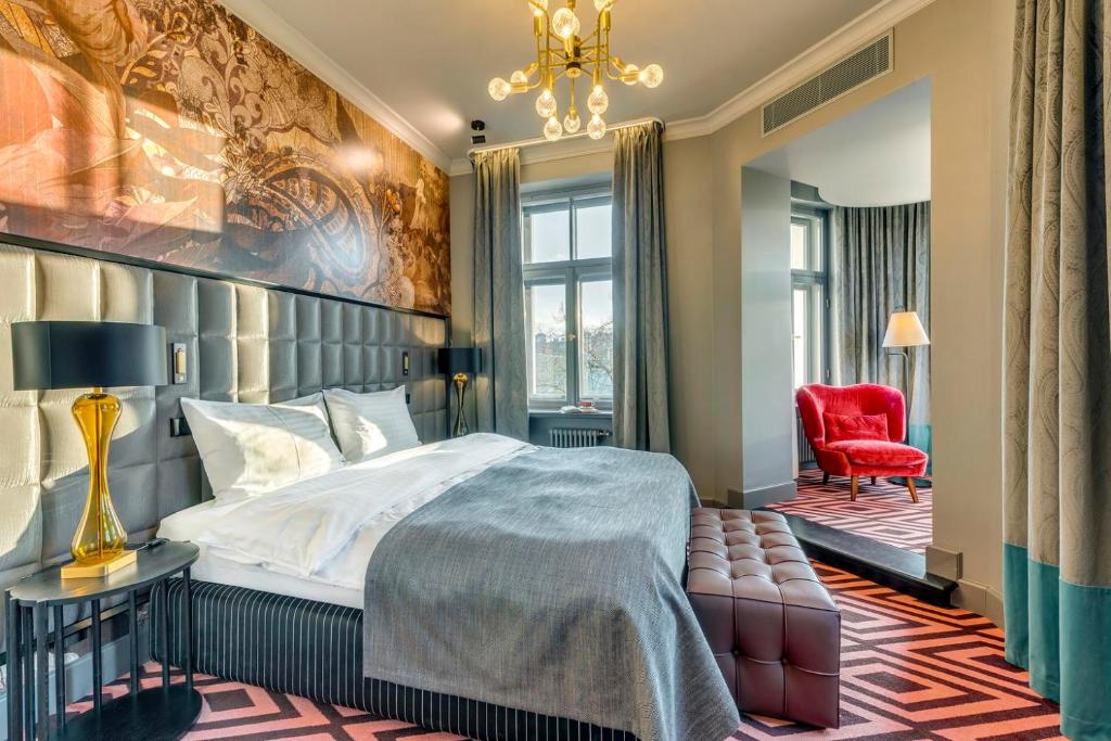a bedroom with a large bed and a red chair at Grand Poet Hotel and SPA by Semarah in Riga