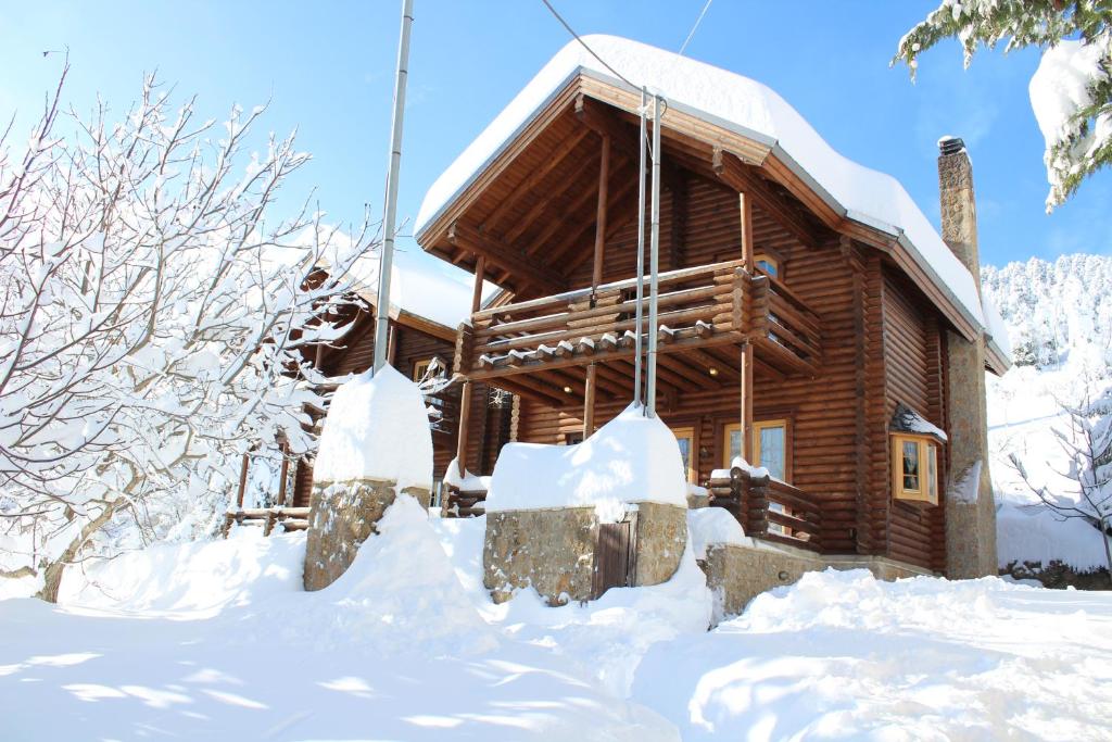a log cabin with snow in front of it at Paradise Chalet in Ano Trikala
