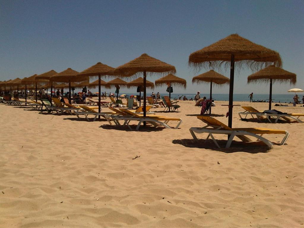 a group of beach chairs and umbrellas on a beach at Casa da Madrinha I in Monte Gordo