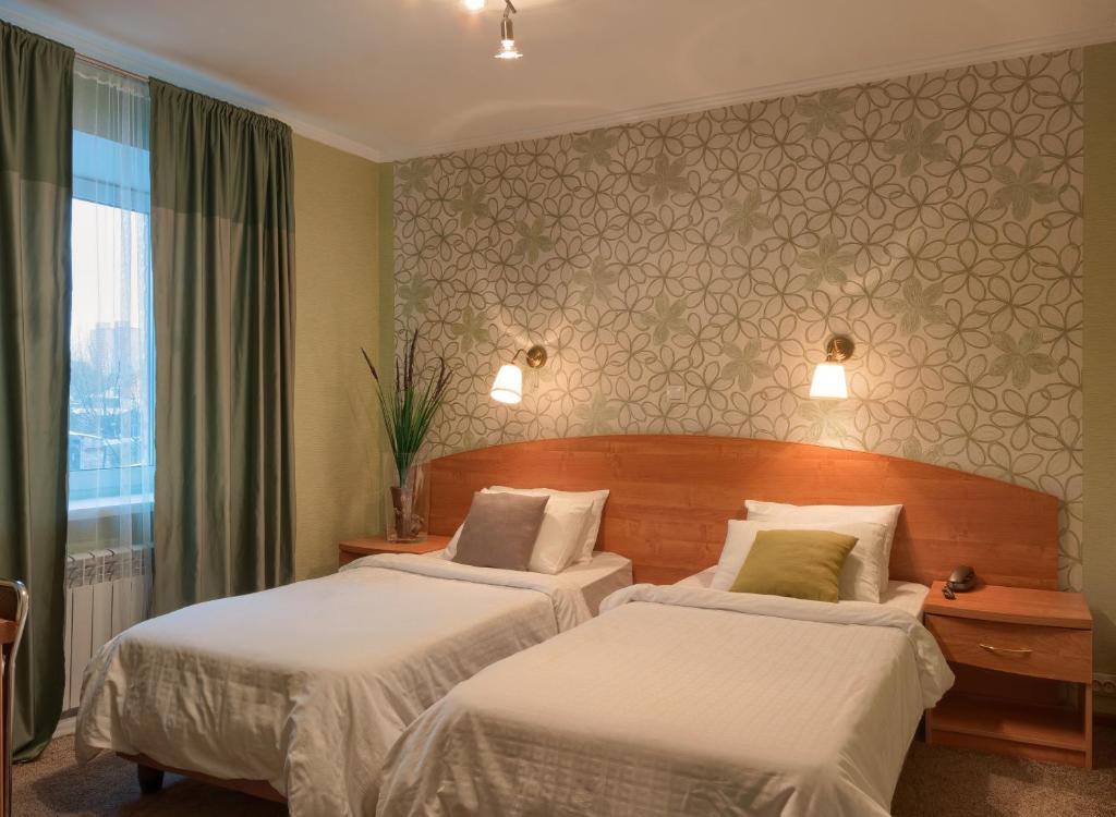 Cette chambre comprend 2 lits et une fenêtre. dans l'établissement Dva Kryla Inn, à Yaroslavl