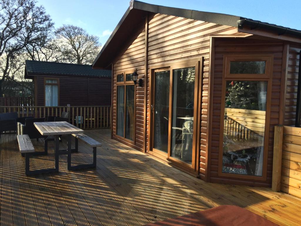 uma cabina de madeira com uma mesa de piquenique no deque em The Warwick lodge em Felton