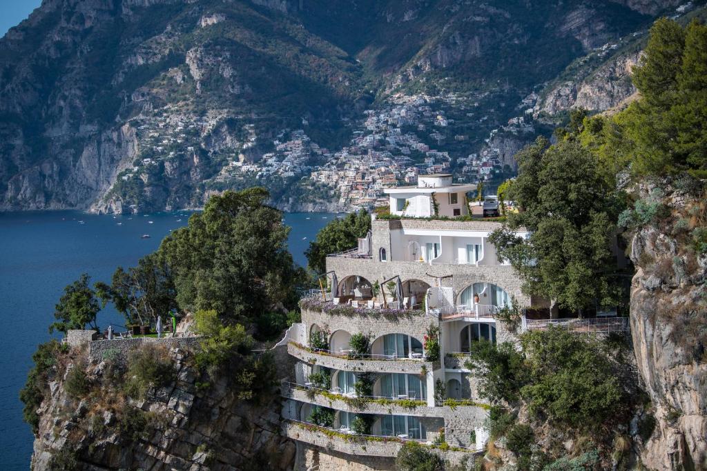 a building on a cliff next to the water at Hotel Piccolo Sant'Andrea in Praiano