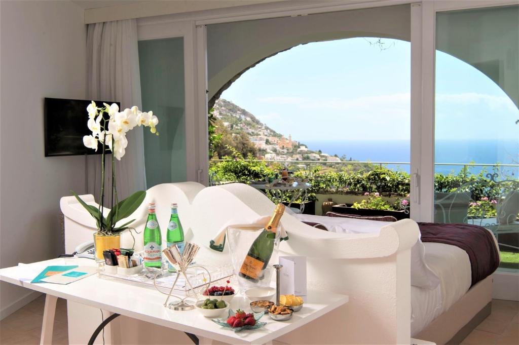 a living room with a white couch and a table with wine bottles at Hotel Piccolo Sant'Andrea in Praiano