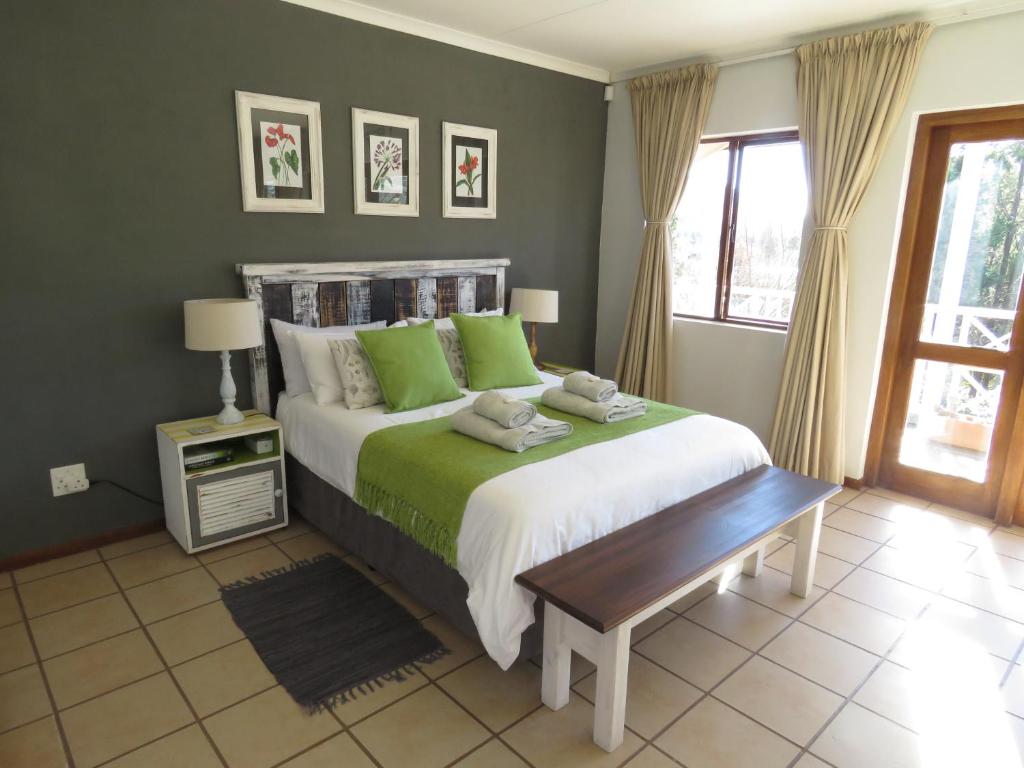 a bedroom with a large bed with green pillows at Fairview Cottages in Clarens