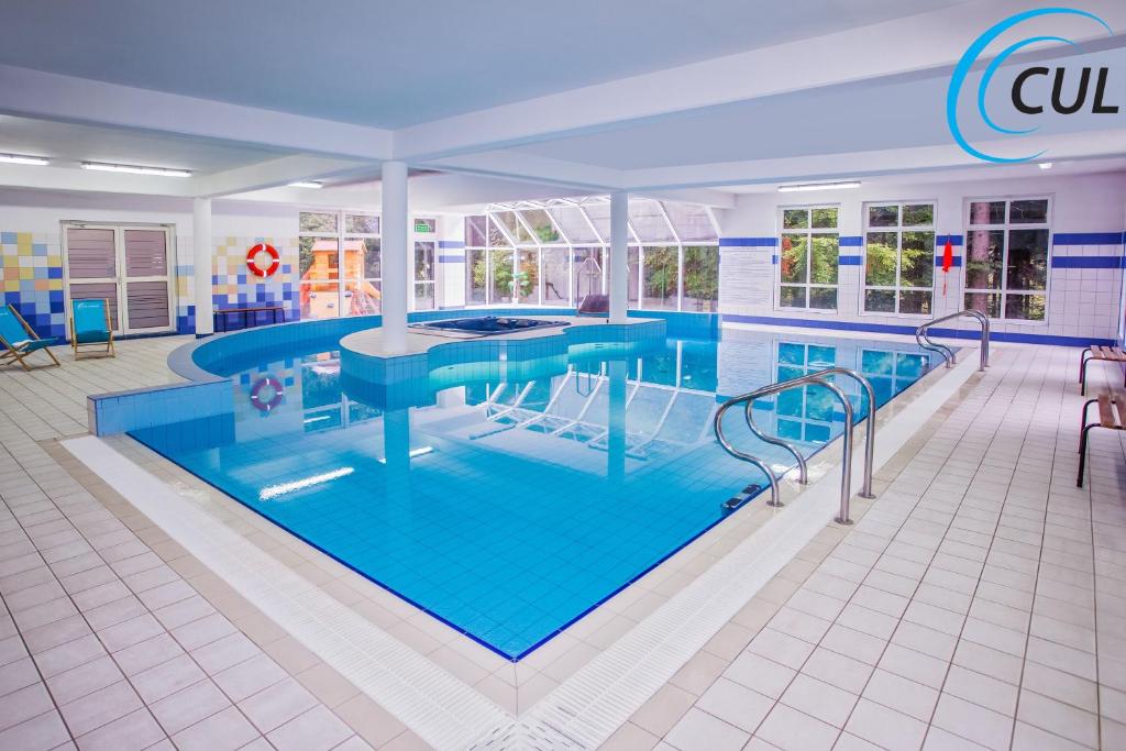 a large swimming pool with blue water in a building at Willa Olimp Retro in Szklarska Poręba