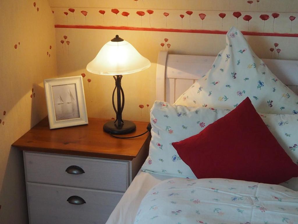 ein Schlafzimmer mit einem Bett mit einer Lampe und einem Bild in der Unterkunft Pension Lüttje Meermaid in Borkum