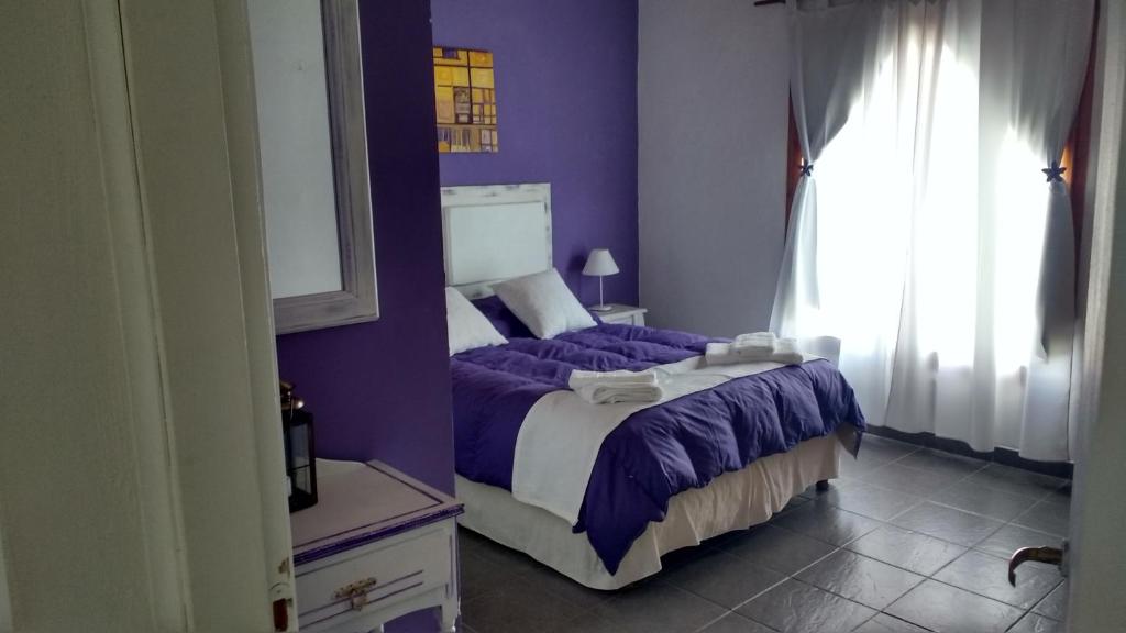 a bedroom with a bed with purple sheets and a window at Los Saucos in El Hoyo