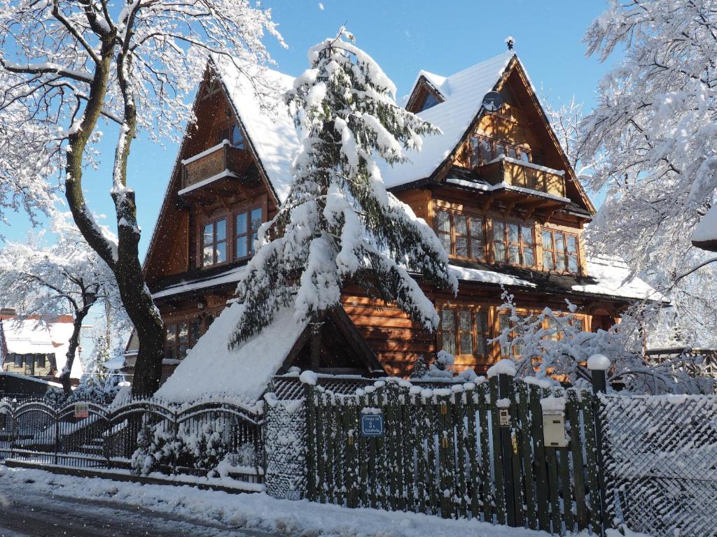 a log cabin in the snow with a fence at Koci Zamek in Zakopane