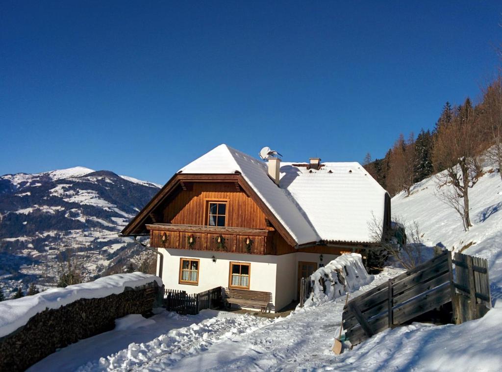 ein Holzhaus mit Schnee auf dem Dach in der Unterkunft Lercherhof in Feld am See