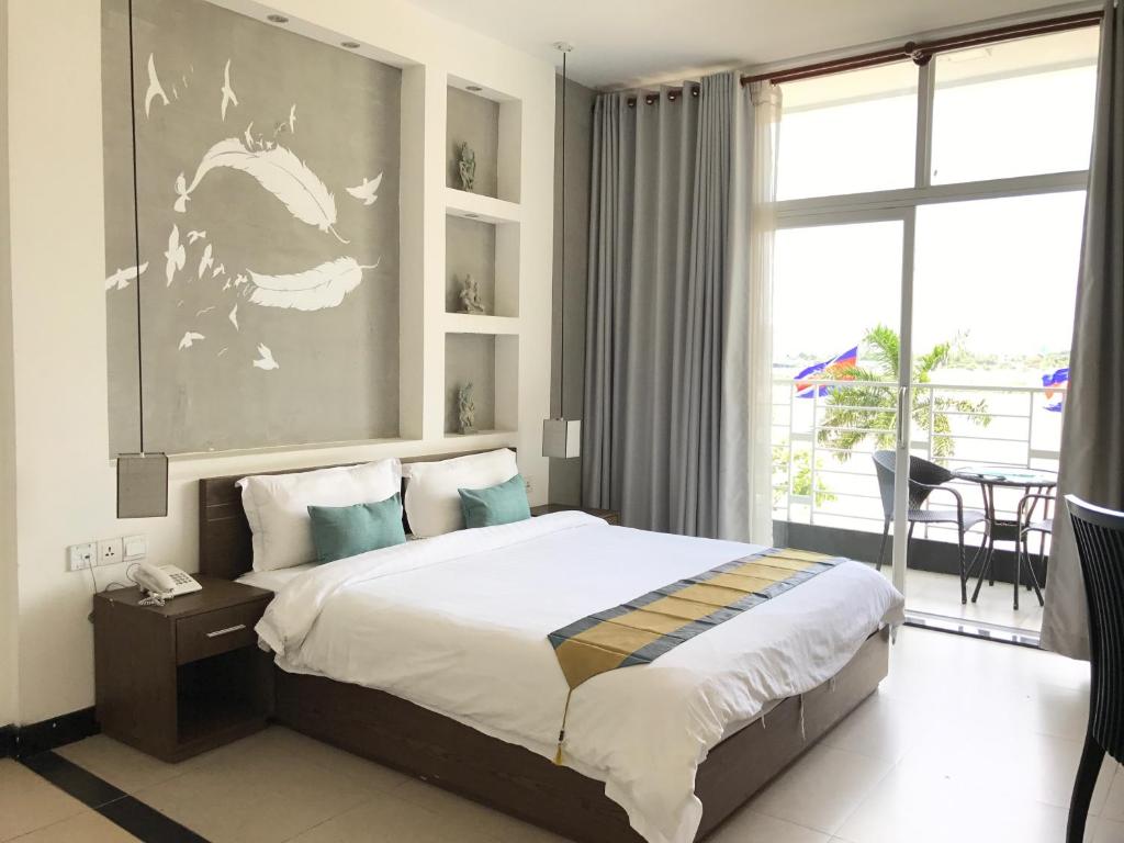 a bedroom with a large bed and a large window at Asiban Quay Boutique Hotel in Phnom Penh