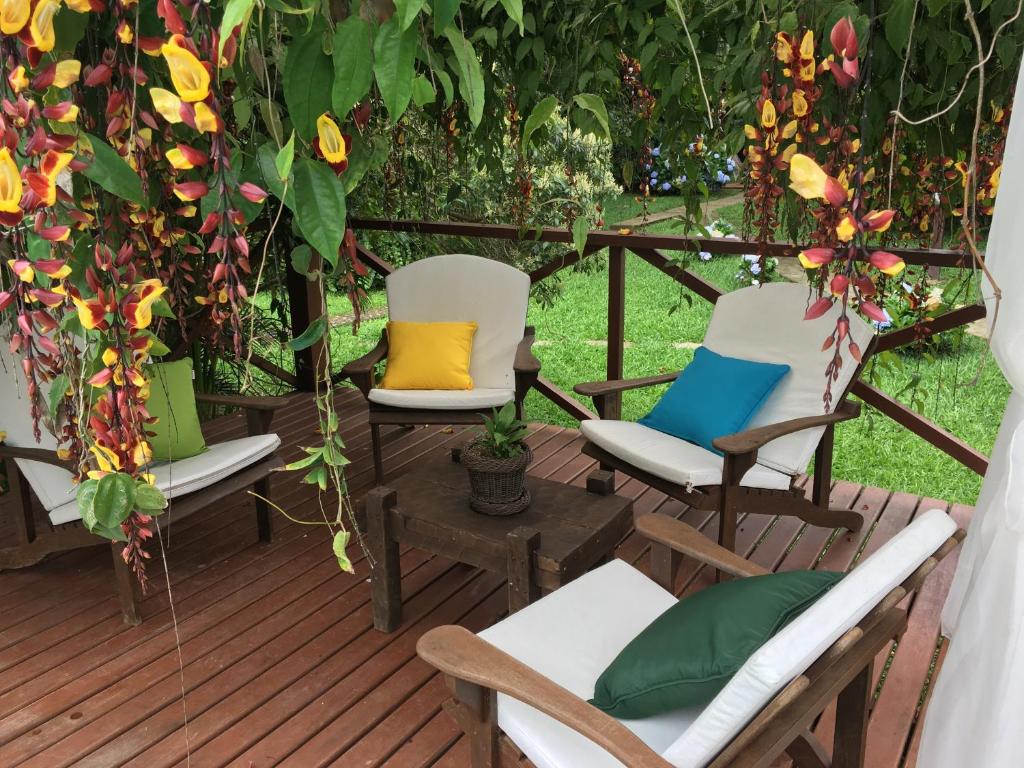 a deck with chairs and a gazebo with flowers at Pousada Recanto do Pinheirão in Visconde De Maua