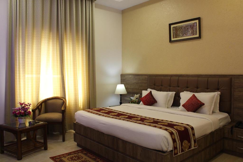 una habitación de hotel con una cama grande y una silla en Regal Hotel and restaurant, en Mathura