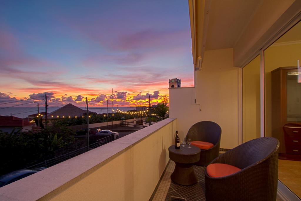 a balcony with a view of the ocean at sunset at Apartamento do Avô Tomás in Madalena do Mar