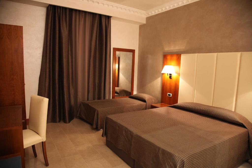 a hotel room with two beds and a chair at Federica's Suite Home in Rome