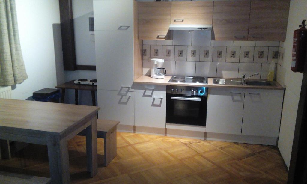 cocina con armarios blancos y mesa de madera en Gasthof zum Nibelungenbauer, en Pöchlarn
