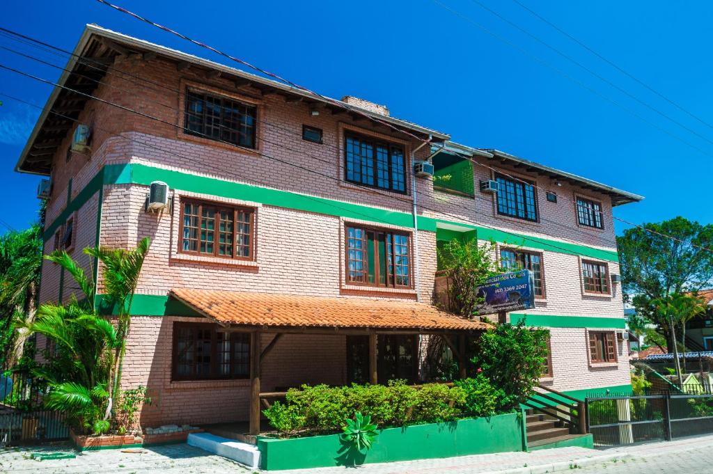 a brick building with green trim on a street at Pousada Residencial dos Corais in Bombinhas