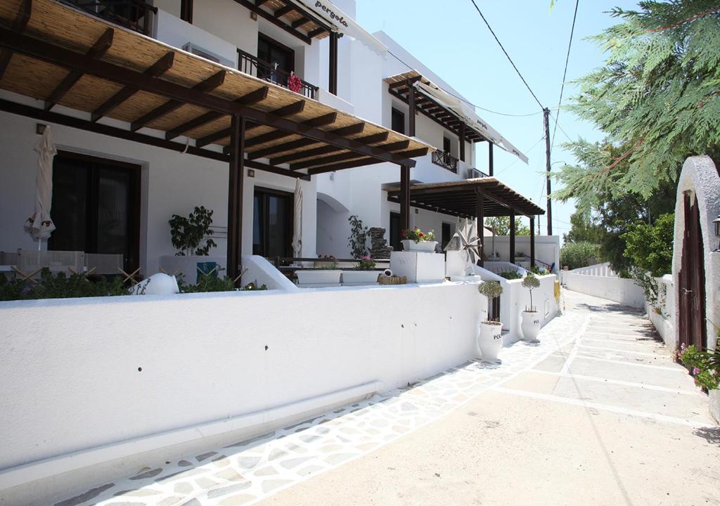 a white house with a white wall and a sidewalk at Pergola in Livadion