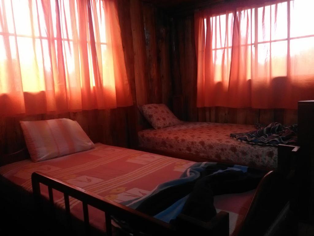 a room with two beds and a window with curtains at Alla Arriba in Las Cruces