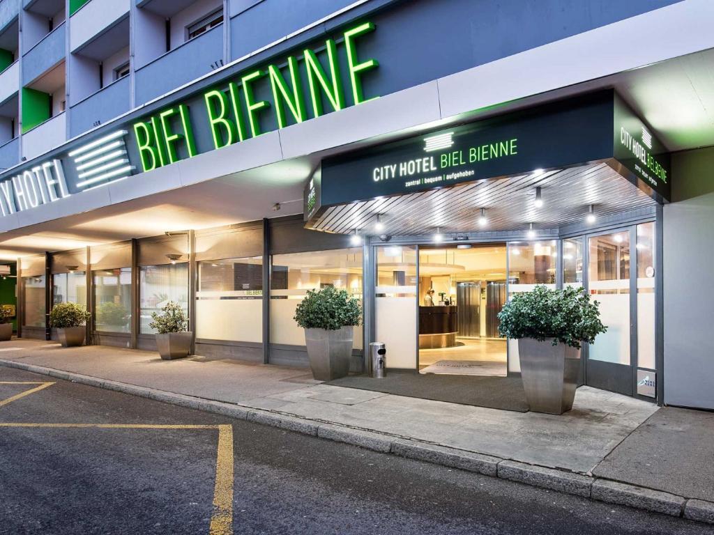 ein Geschäft vor einem Gebäude mit Topfpflanzen in der Unterkunft City Hotel Biel Bienne Free Parking in Biel