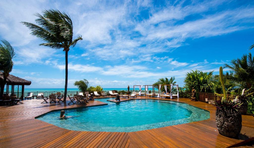 una piscina en la terraza de un complejo con una palmera en Hotel Sombra e Água Fresca en Pipa