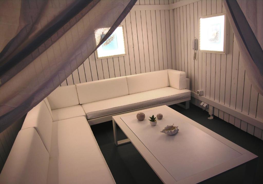 a living room with a white couch and a table at Aeolos Art & Eco Suites Adults Only in Imerovigli