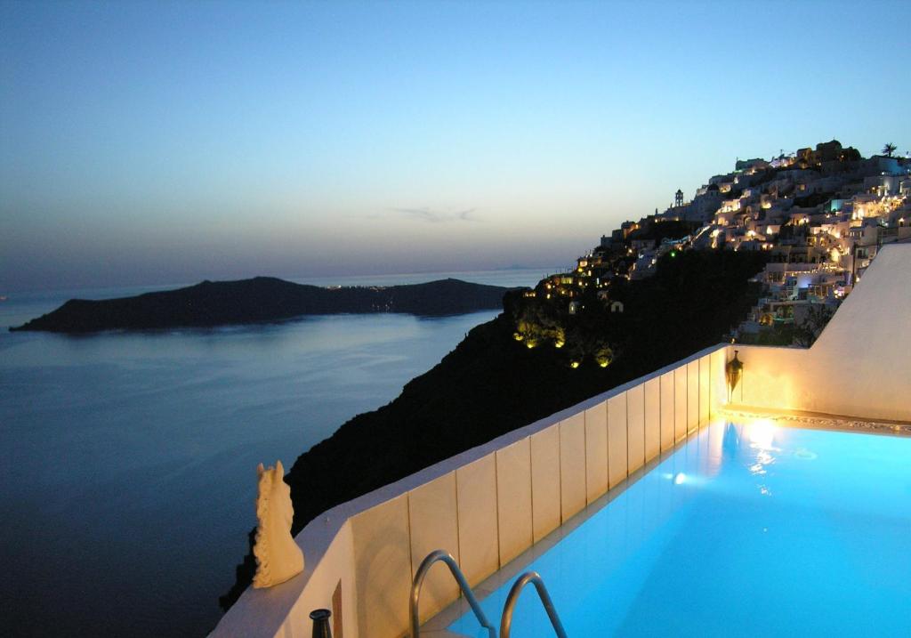 a pool with a view of the ocean at night at Aeolos Art & Eco Suites Adults Only in Imerovigli