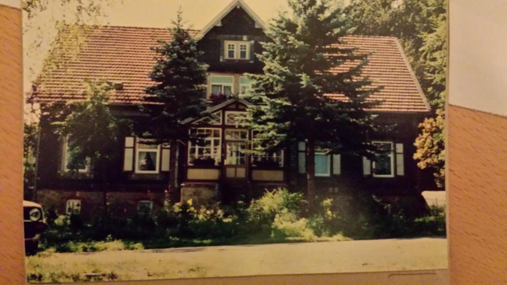 una vieja foto de una casa con árboles delante en Zur Alten Oberförsterei, en Benneckenstein