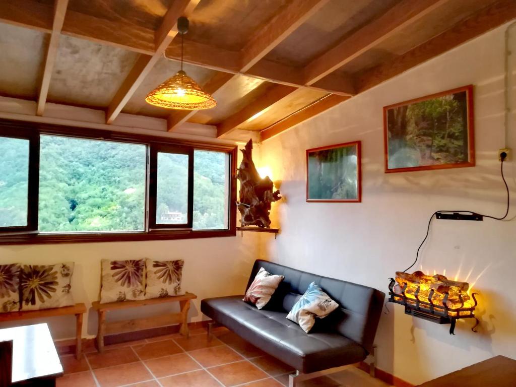 a living room with a black leather couch and windows at Casa La Montaña in El Cedro