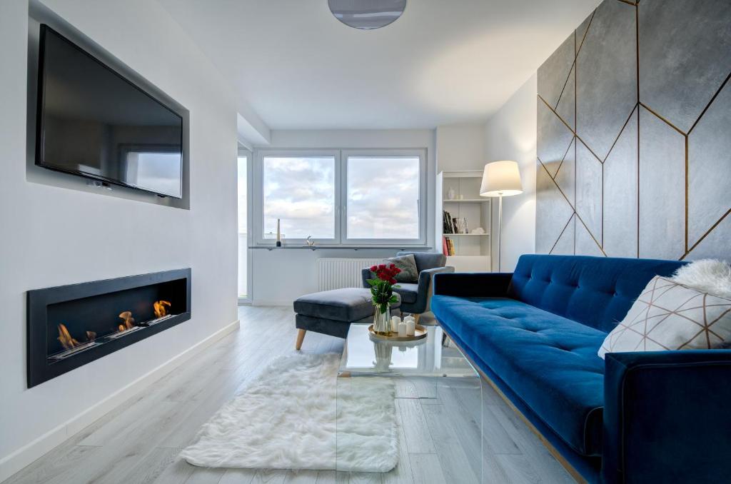 a living room with a blue couch and a fireplace at Modern Place Apartament przy plaży in Gdynia