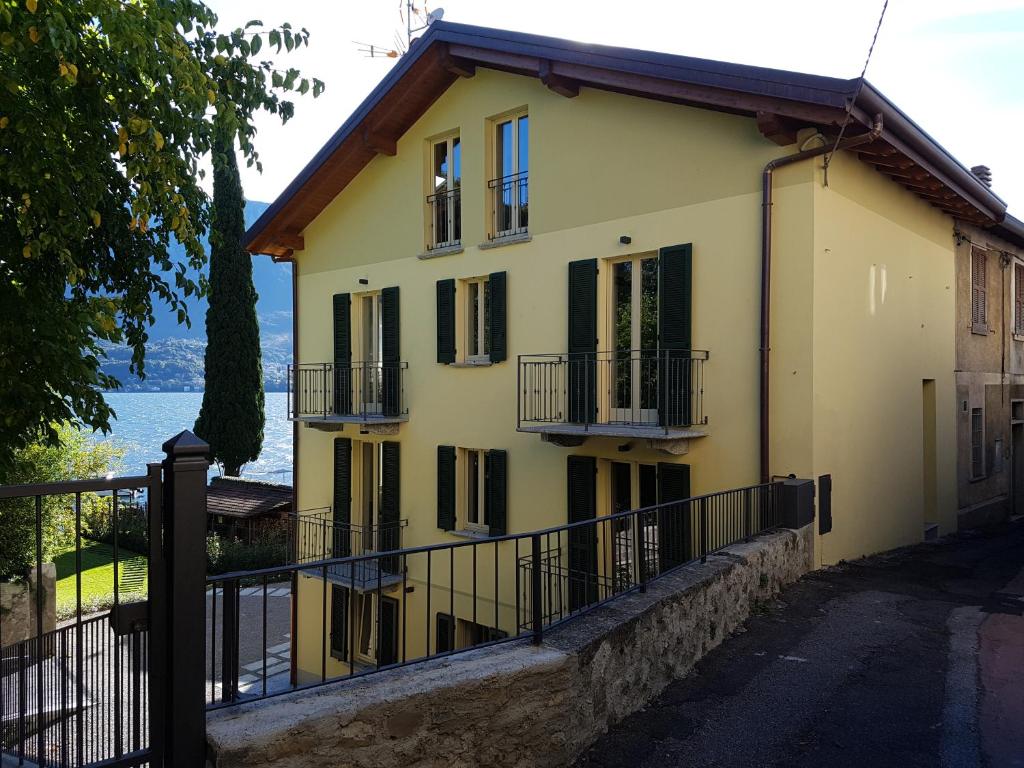 a yellow house with balconies and a fence at Residence Matilde in Oliveto Lario