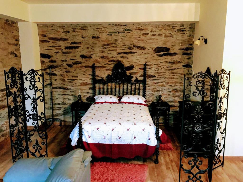 um quarto com uma cama e uma parede de pedra em Casa da Escola Antiga em Manteigas