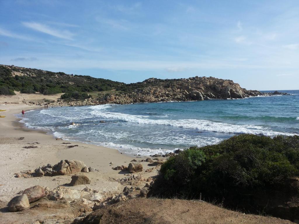 una spiaggia con rocce e l'oceano in una giornata di sole di VIlla Ulivi a Chia