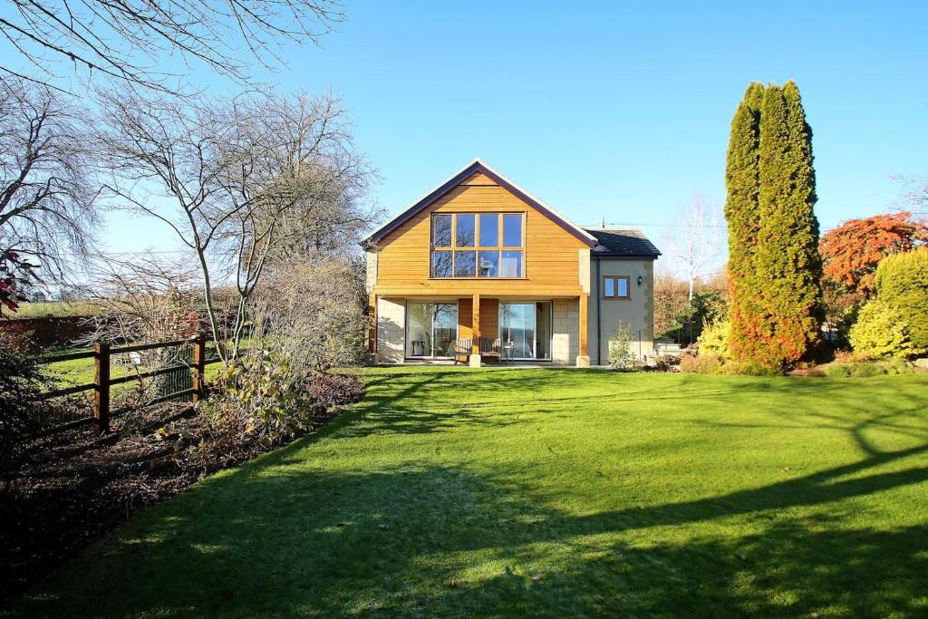 a house on a green lawn with a fence at Dove Lodge in Painswick