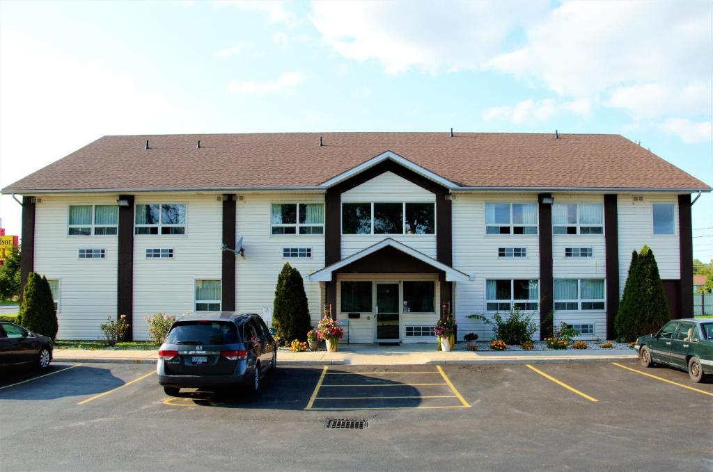 un gran edificio blanco con coches aparcados en un aparcamiento en Royal Windsor Motel, en Windsor