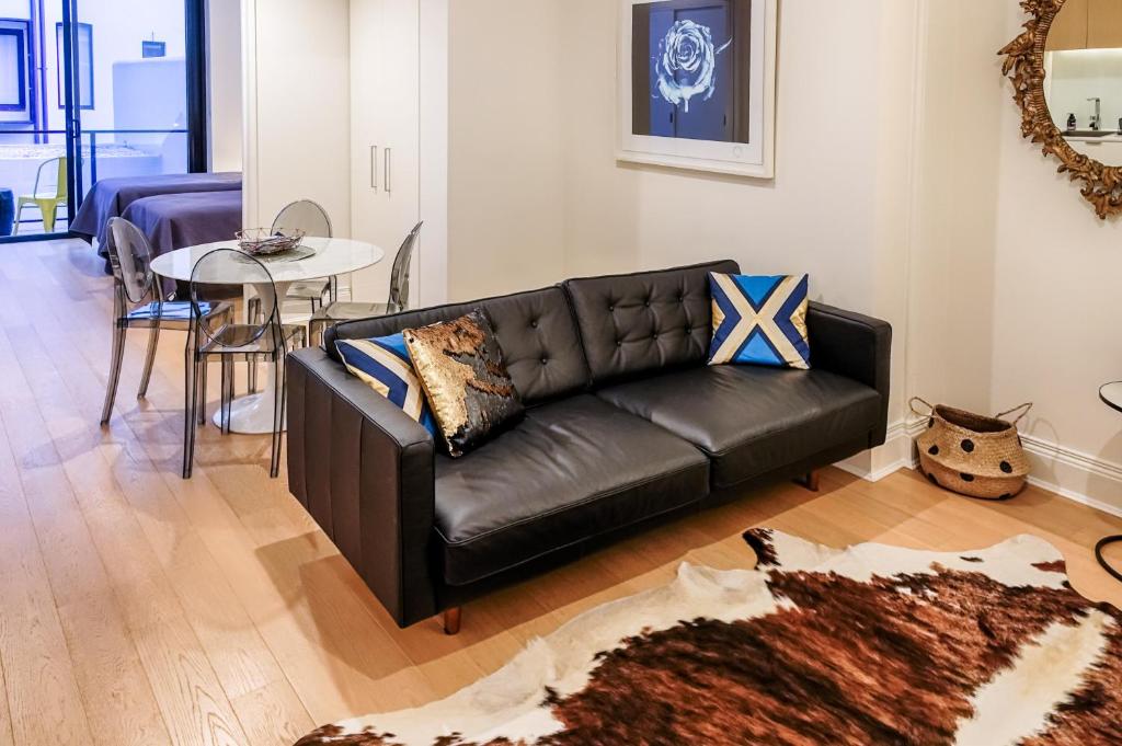 sala de estar con sofá de cuero negro y mesa en Orange Stay Apartments Potts Point, en Sídney