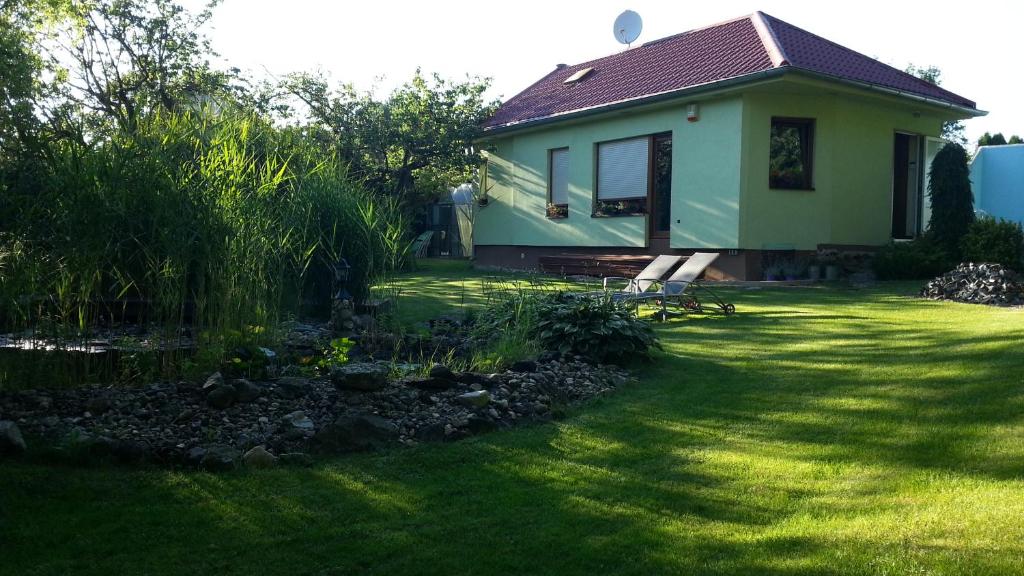 ein grünes Haus mit einem Hof mit einem Teich in der Unterkunft Prázdninový dům u lesa in Znojmo