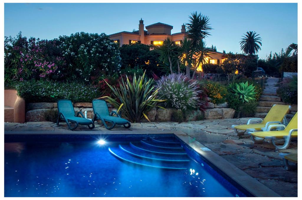 a swimming pool with chairs and a house in the background at Quinta do Sotavento in Moncarapacho