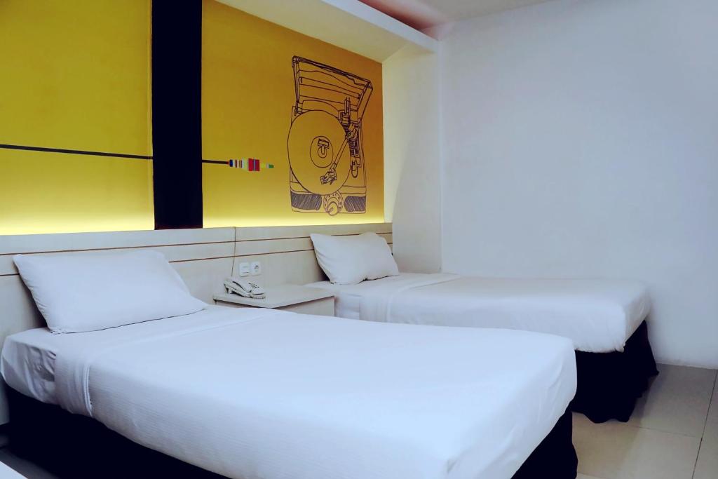 twee bedden in een kamer met een schilderij aan de muur bij Front One Inn Sidoarjo in Sidoarjo