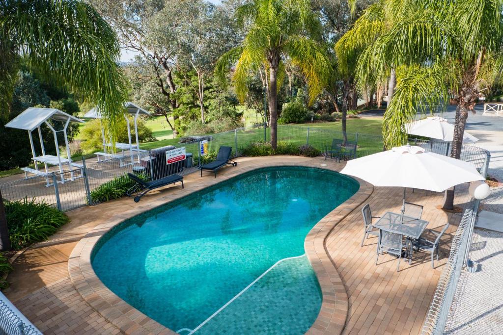 una piscina con sombrilla, mesa y sillas en Commercial Golf Resort, en Albury