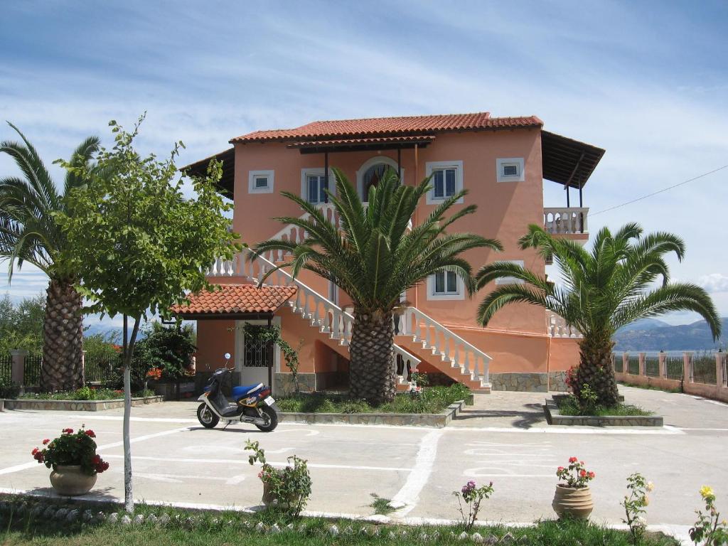 a house with palm trees and a scooter parked in a parking lot at Neptune Resort in Kavos