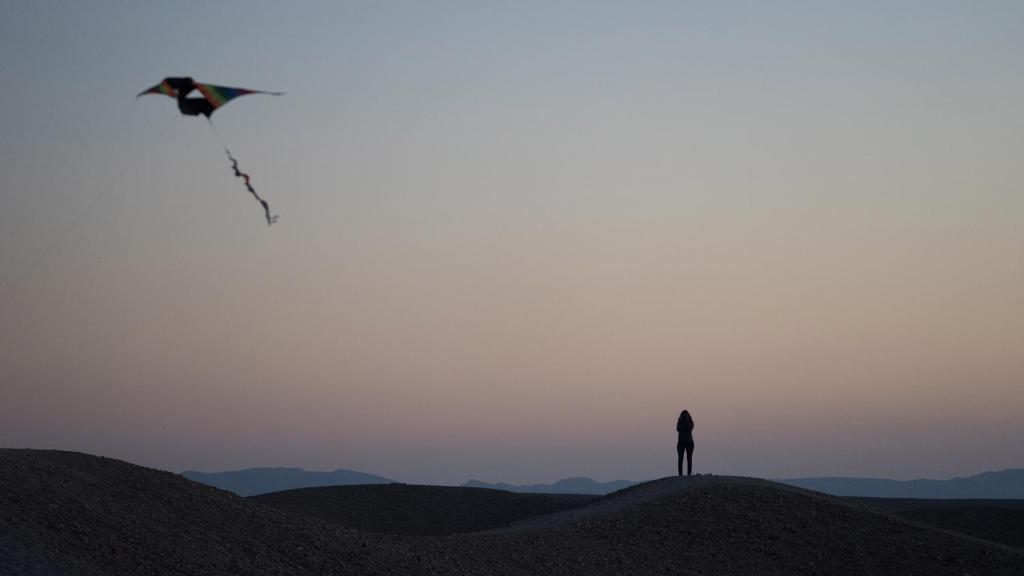 una persona che vola un aquilone in cima a una collina di Desert Days mud cabin's Resort a Zuqim