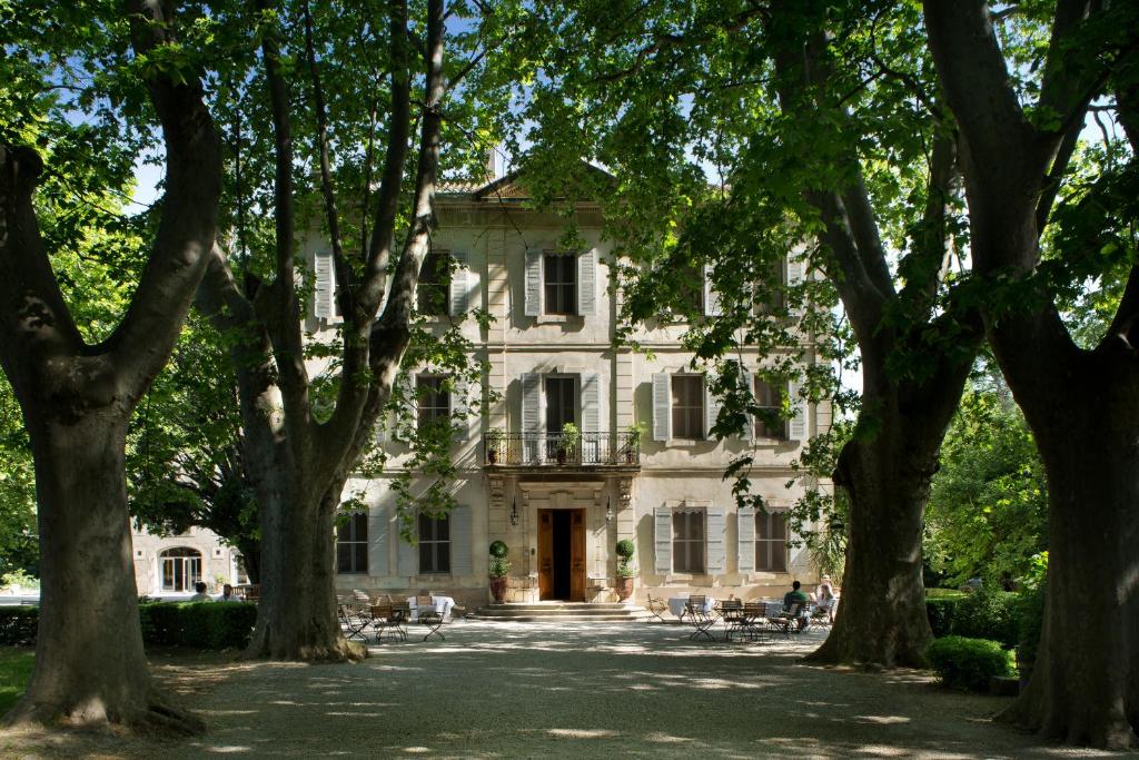 een oud huis met bomen ervoor bij Hotel Château Des Alpilles in Saint-Rémy-de-Provence