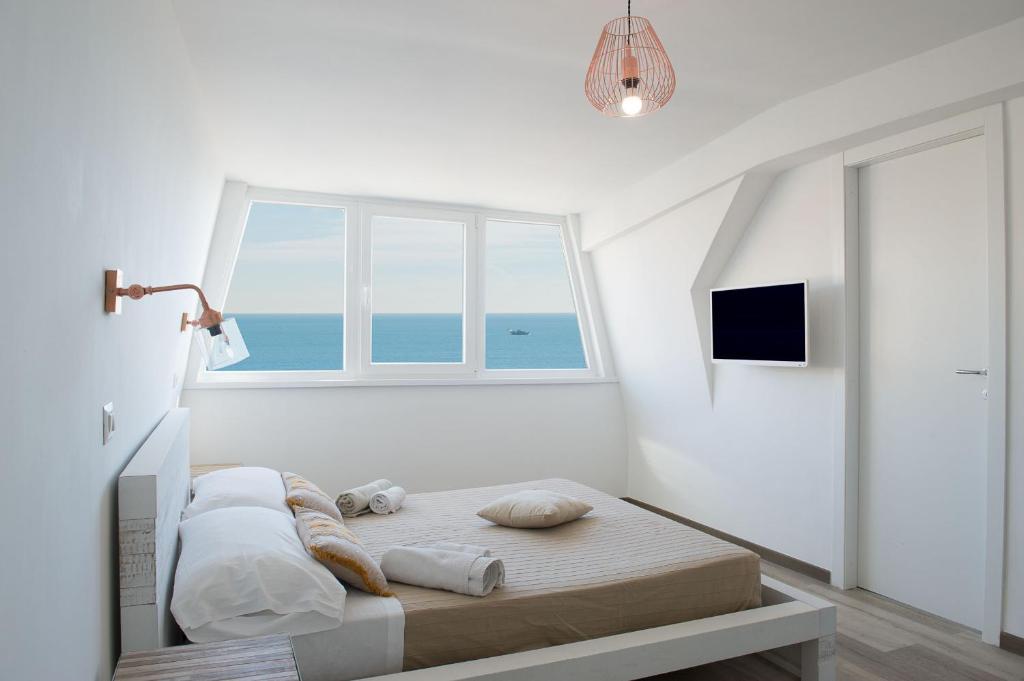 a white bedroom with a bed and a window at Appartamento Mykonos in Lido di Ostia