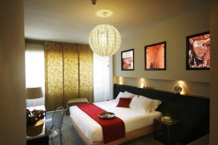 a bedroom with a large bed and a chandelier at Hotel K2 Bellaria in Bellaria-Igea Marina