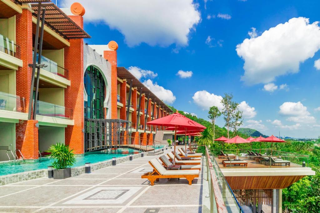 un hotel con piscina, sillas y sombrillas en Aonang Phu Pi Maan Resort & Spa - SHA Extra Plus en Ao Nang Beach