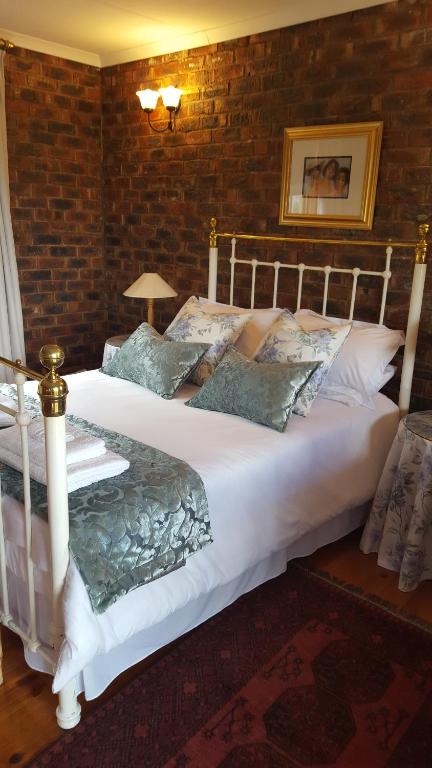 two beds in a bedroom with a brick wall at Clarens Cottages in Clarens
