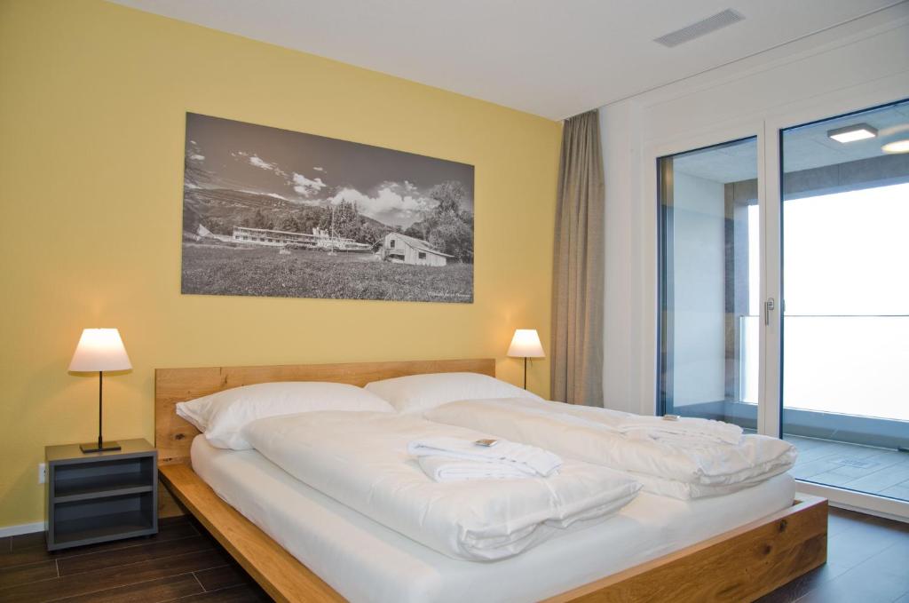 Apartment Silberdistel - GriwaRent AG في إنترلاكن: غرفة نوم بسرير كبير مع شراشف بيضاء