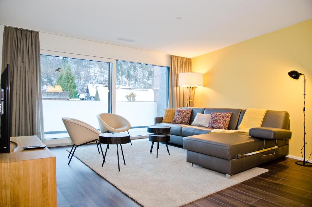 ein Wohnzimmer mit einem Sofa, einem Tisch und Stühlen in der Unterkunft Apartment Ankebälleli - GriwaRent AG in Interlaken