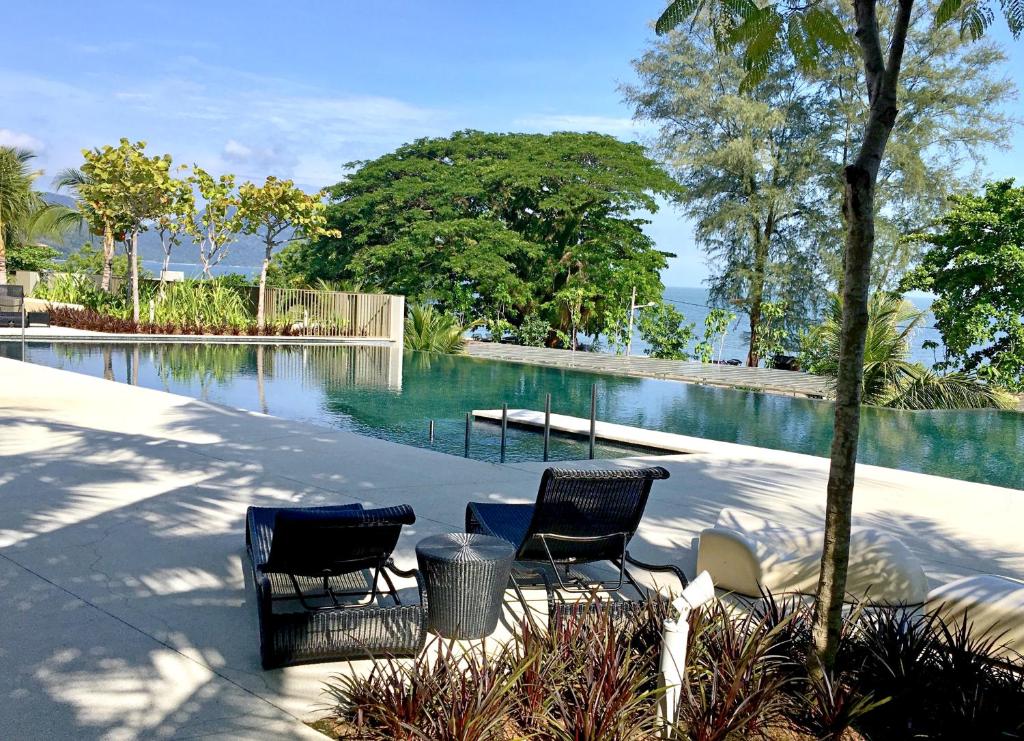 two chairs and a table next to a swimming pool at By The Sea Suite,Batu Ferringhi in Batu Ferringhi